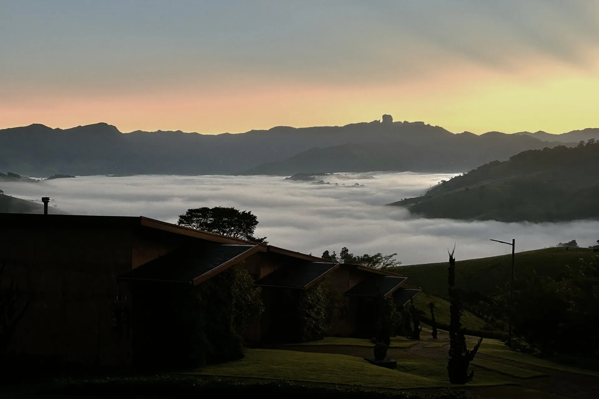 Amanhecer com mar de nuvens e Pedra do Baú ao fundo, vista da Pousada Terra dos Pássaros em São Bento do Sapucaí